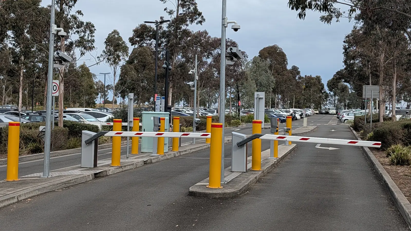 Boom gates down across the entry lane of the Tallawong Park and Ride car park, with rows of parked cars filling the lot behind